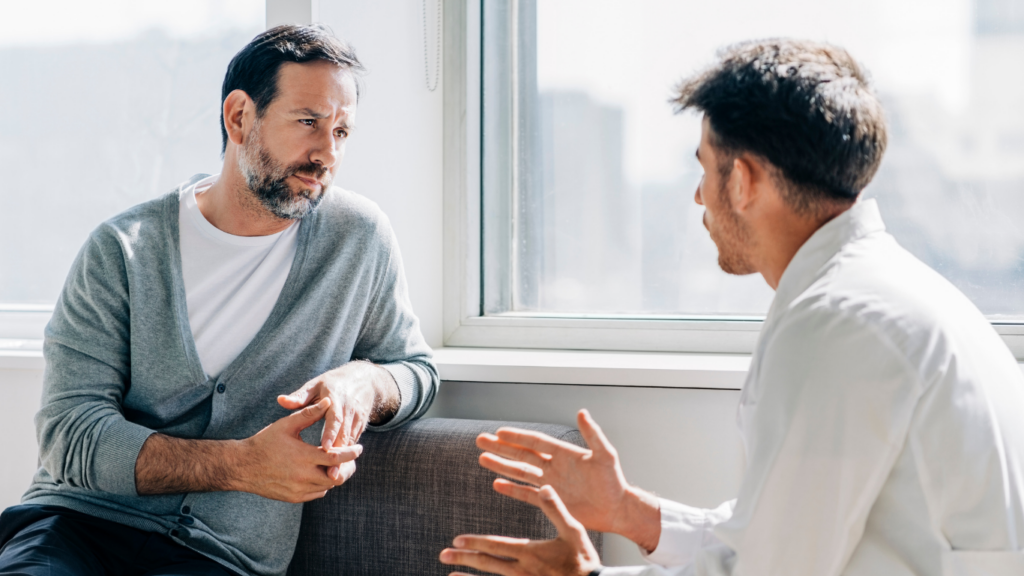 Two men sit across from each other. The patient has tried several psychologists in Calgary, but feels he is being heard at Assured Psychology.